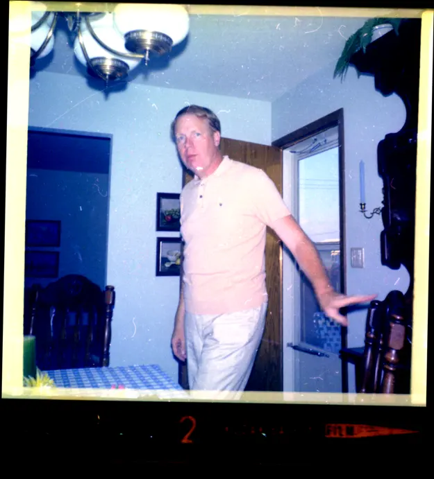 A photograph of a man surprised by the photographer as he was about to sit at the table.