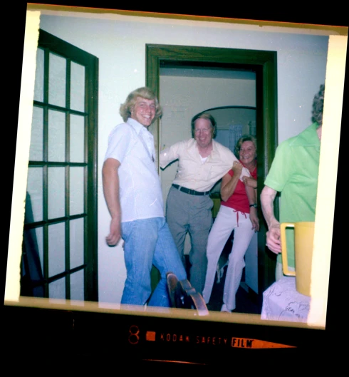 A photograph of a three people smiling as one tugs the other while the third looks at the camera.