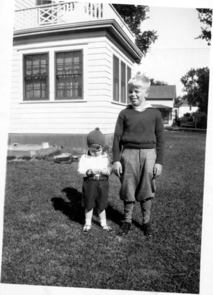 A photograph of two boys standing in the back yard, neither looks at the camera.