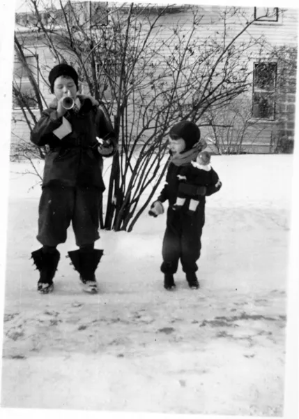 A photograph of a boy riding a tricycle in the back yard.