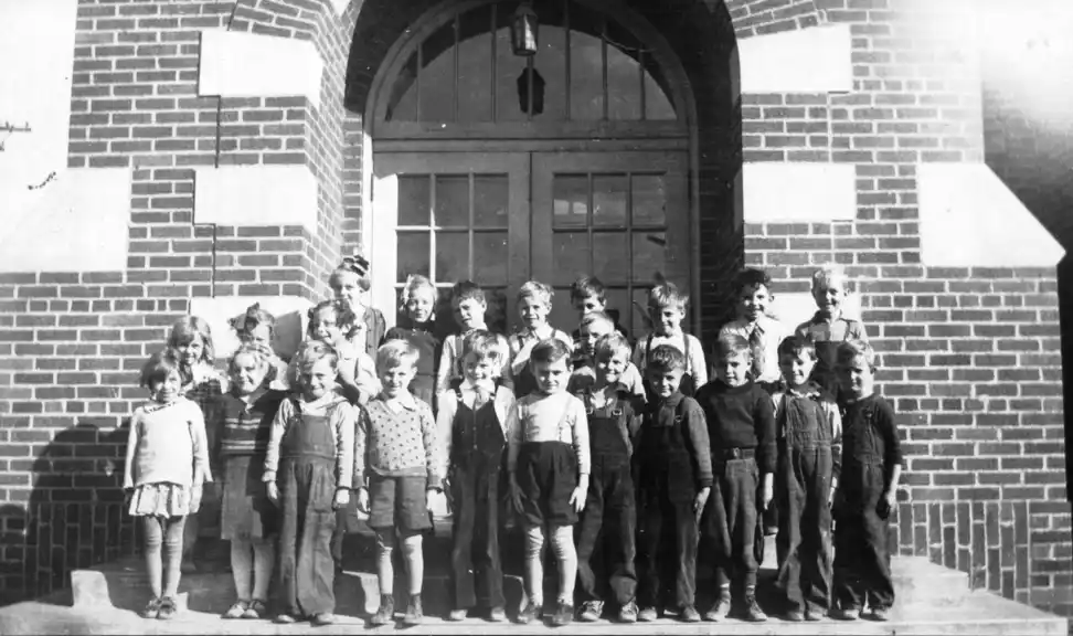 A photograph of girls and boys lined up in fron of the school door.