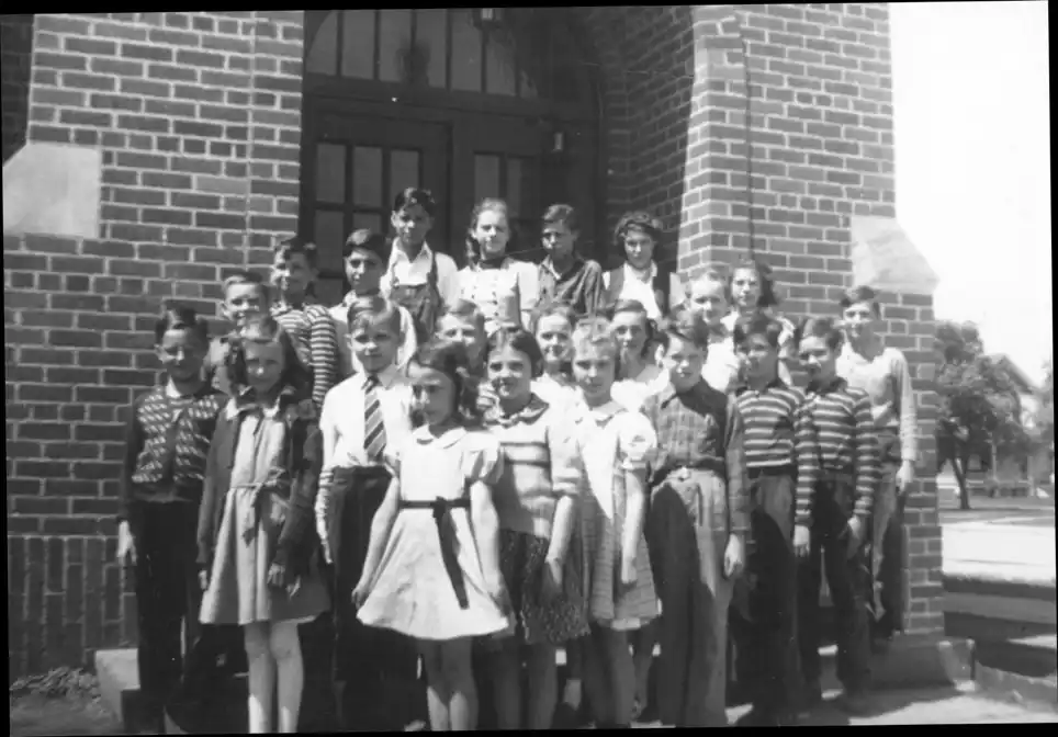 A photograph of the fifth grade class standing at the school entrance.