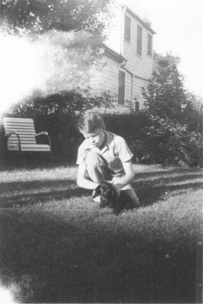 A photograph of a boy and a puppy in the backyard.