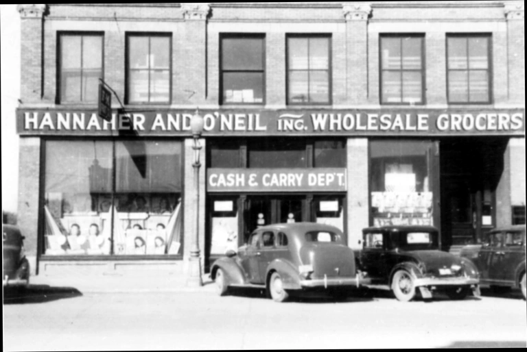 A photograph of a business with a sign for HANNAHER AND O'NEIL INC. WHOLESALE GROCERS spanning the width of three addresses.