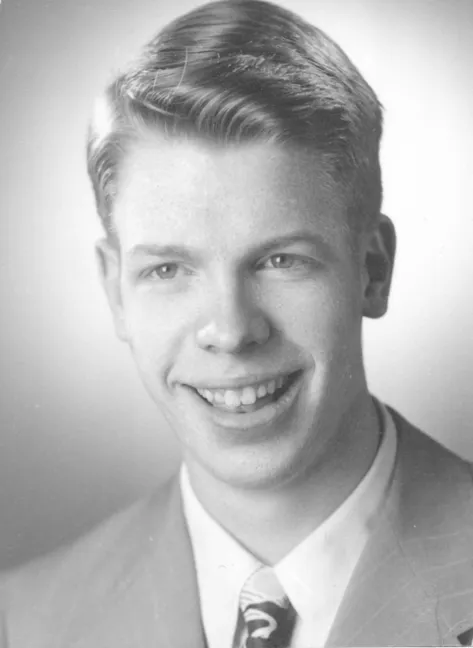 A photograph of a broadly smiling white man, taken for his senior year yearbook.