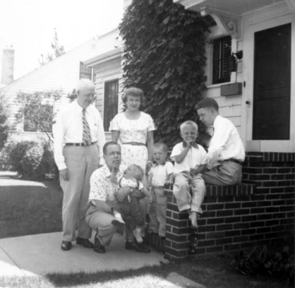 A photograph of an extended family on the brick front steps of a house.