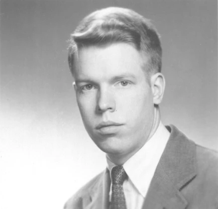 A photograph of the face of a coiffed young man wearing a suit and tie.