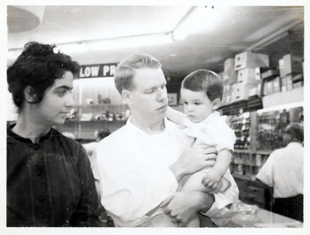 A photograph of a dark-haired woman, a red-haired man, and their son as they visit a camera store.