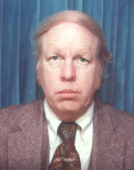 A photograph of a middle-aged white man wearing a tie and three-piece suit.
